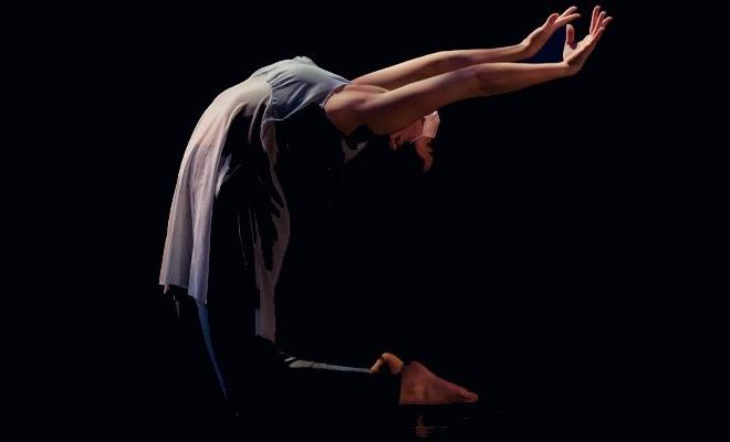 Dance student in dramatic movement on black background